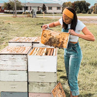 Cindy Moore holding honey and bees a beehive